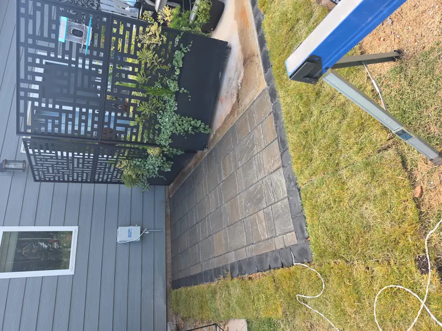 New sod installation around a garden bed on a Concord, NC property, framing a black arbor